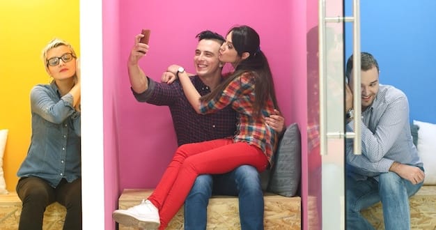 A group of friends taking a selfie amidst a vibrant, floor-to-ceiling projected art installation, emphasizing the social media aspect.
