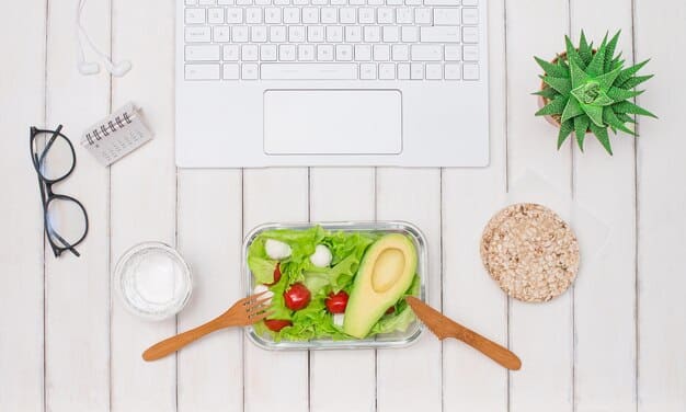 A colorful, healthy salad and a glass of water on a clean desk, symbolizing nutritious choices and hydration for energy and focus in a work setting.