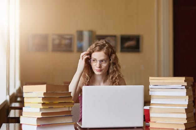 A student looking determined and focused, surrounded by books and a laptop, with a thoughtful expression suggesting deep concentration on their writing.