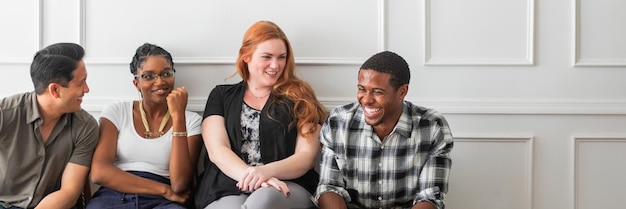 A diverse group of four individuals: one smiling, one thoughtfully listening, one gesturing, and another taking notes, seated around a table, symbolizing a productive and supportive conversation within a healthcare or policy discussion.