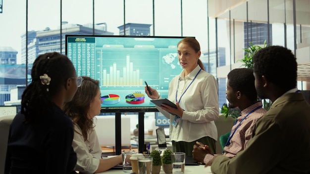 A data analyst meticulously reviewing charts and graphs on multiple screens, focusing on employee wellness program metrics and showing positive trends in a professional office setting.
