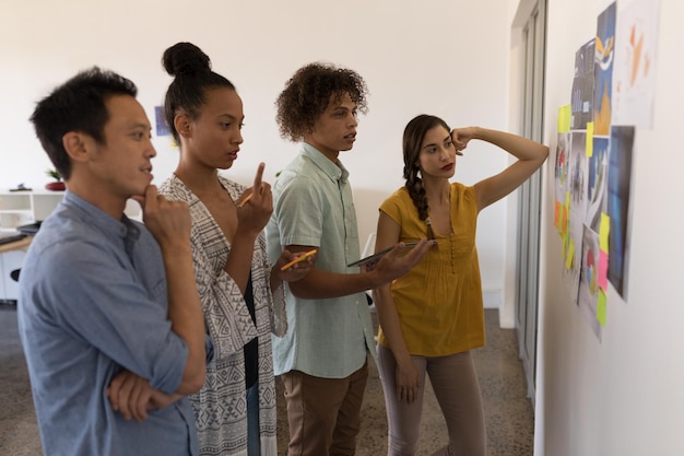 A diverse group of young professionals in a brainstorming session, using a whiteboard and sticky notes, showing clear communication and collaborative problem-solving.
